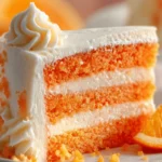 Orange Creamsicle Cake slice with vanilla frosting and bright orange layers
