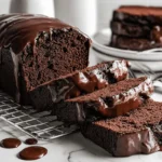 Moist chocolate pound cake with glossy ganache glaze sliced on a cooling rack