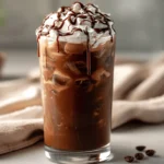 Iced mocha coffee in a tall glass with ice, whipped cream, and chocolate drizzle