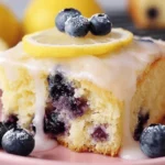 Moist slice of lemon blueberry sheet cake with lemon glaze, topped with lemon slice and fresh blueberries