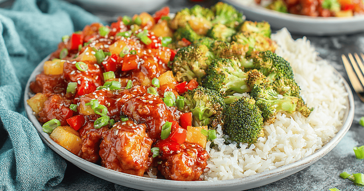 A plate of Easy Sweet Hawaiian Crockpot Chicken served with white rice and roasted broccoli, topped with green onions and sesame seeds